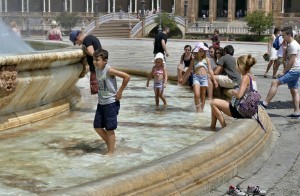 Gente en las fuentes de Sevilla a causa del clima veraniego.